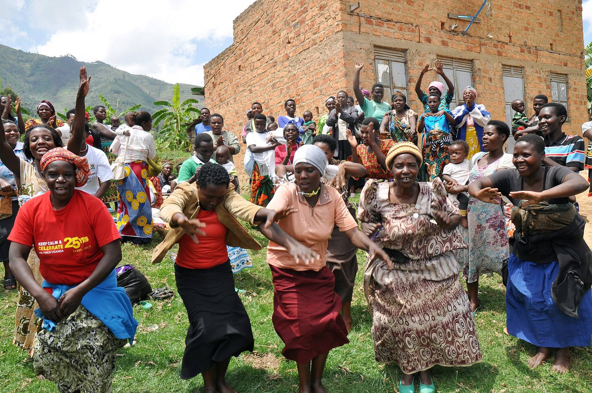 A crowd of women in bright clothes cheering and dancing outdoors